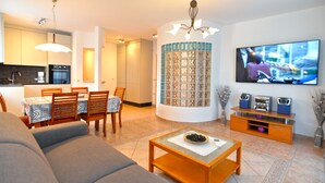 A modern living room with a sofa, coffee table, and TV. There is a kitchen area with cabinets and a dining table. - Apartment 1299/12346 (Istria - Vrsar), 300m from the beach (Vrsar)