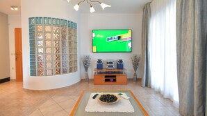 A living room with a television mounted on the wall, a coffee table with a bowl of snacks, and a decorative wall panel. - Apartment 1299/12346 (Istria - Vrsar), 300m from the beach (Vrsar)