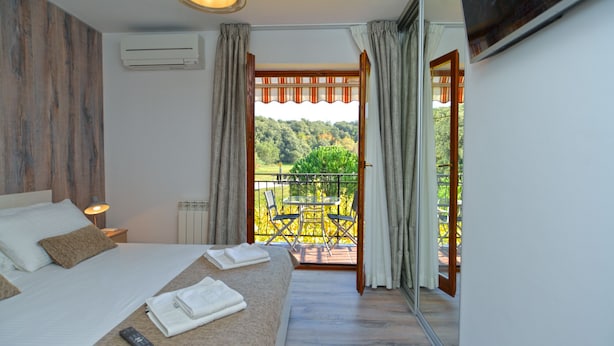A bedroom with a bed, bedside table, and a view of a balcony with chairs and a table. - Apartment 1299/12346 (Istria - Vrsar), 300m from the beach (Vrsar)