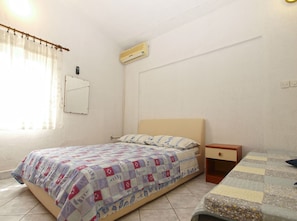 A small, simple room with a bed, a bedside table, and an air conditioning unit. - Apartment 1306/12413 (Istria - Fažana), 500m from the beach (Fažana)