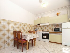 Cocina compacta con una mesa de comedor, sillas, microondas, horno y armarios.