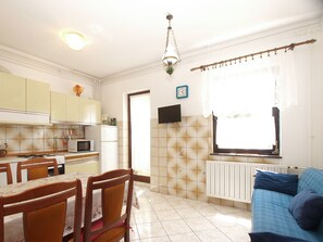 Una cocina compacta con zona de comedor, un televisor montado en la pared y una ventana con cortinas.