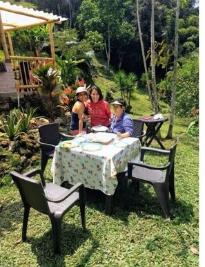Enjoy a casual meal in a serene outdoor setting surrounded by lush greenery and natural beauty.