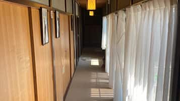 Un pasillo con puertas correderas de madera, suelo alfombrado y una lámpara colgante.