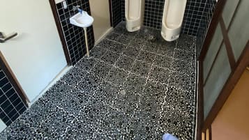 Un bagno maschile con due orinatoi, un lavandino e un pavimento piastrellato.
