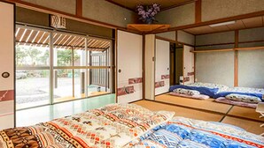 Une pièce de style japonais traditionnel, avec un sol recouvert de tatamis, des portes coulissantes et un lit doté de draps à motifs.