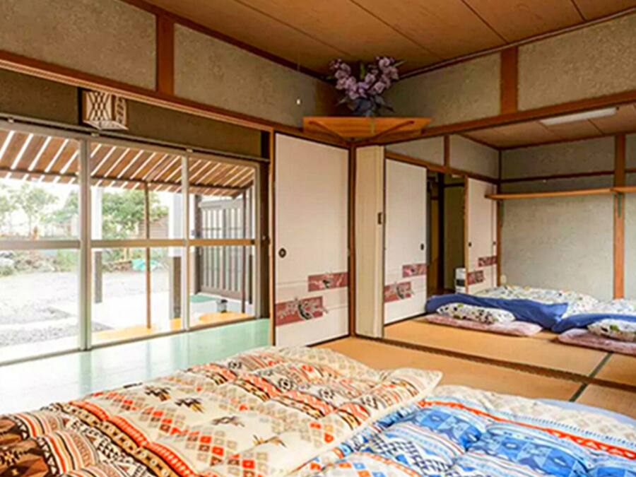Una habitación tradicional japonesa con suelo de tatami, puertas correderas y una cama con ropa de cama estampada.