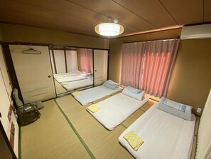 Een hotelkamer met drie eenpersoonsbedden, een grote spiegel, een hanglamp en een schuifdeur.