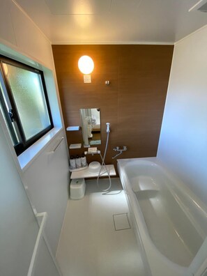 Kombinasi shower/bathtub, sandal,  dan handuk