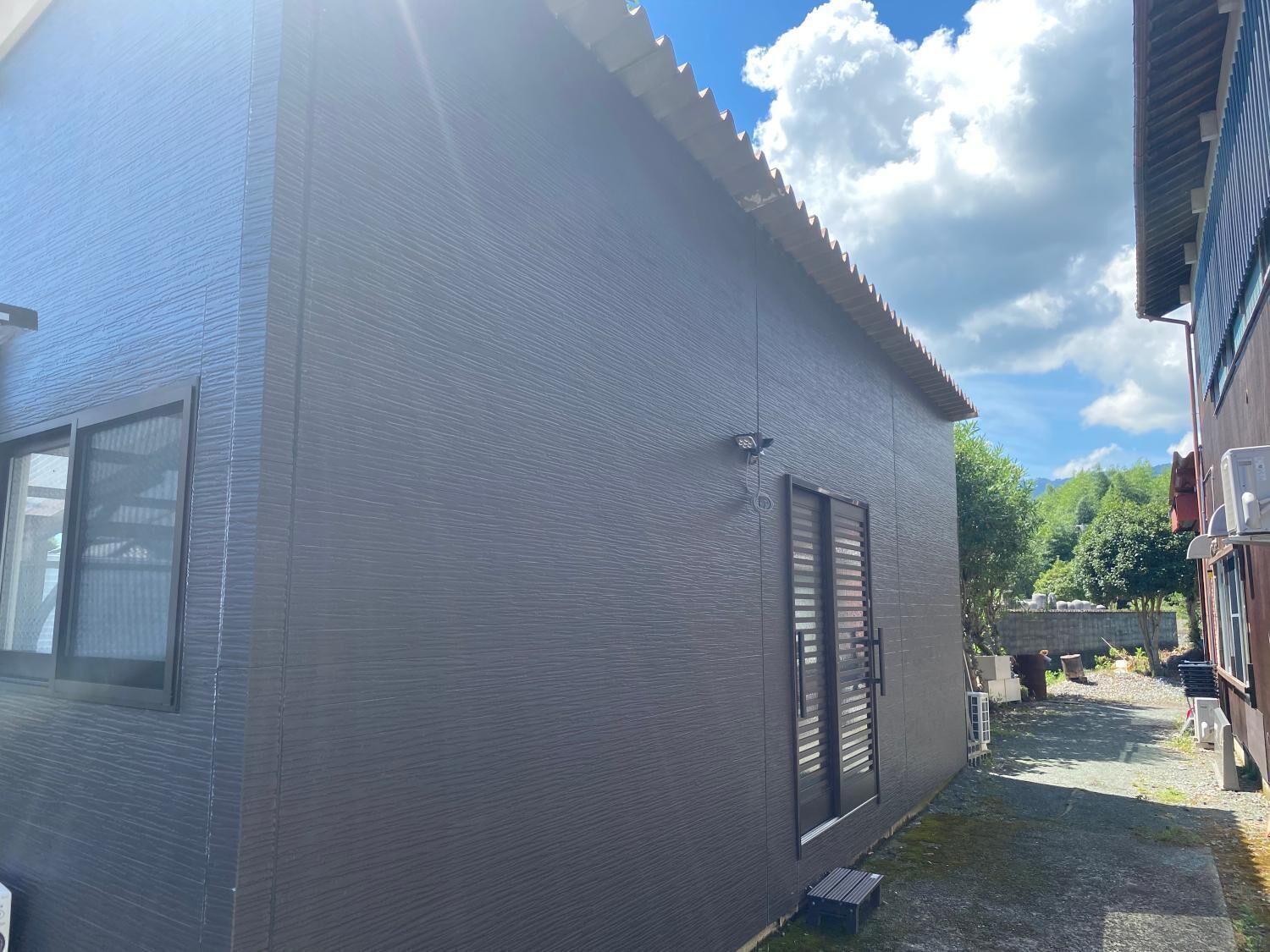 Un edificio moderno con facciata grigia, ampie finestre e un piccolo cortile.