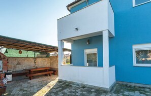 Un edificio de dos pisos con fachada azul y un patio cubierto.