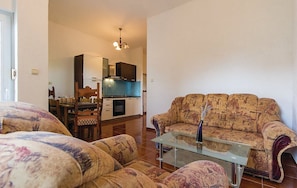 Una sala de estar con sofá, una mesa de centro de vidrio y una zona de comedor con mesa y sillas.