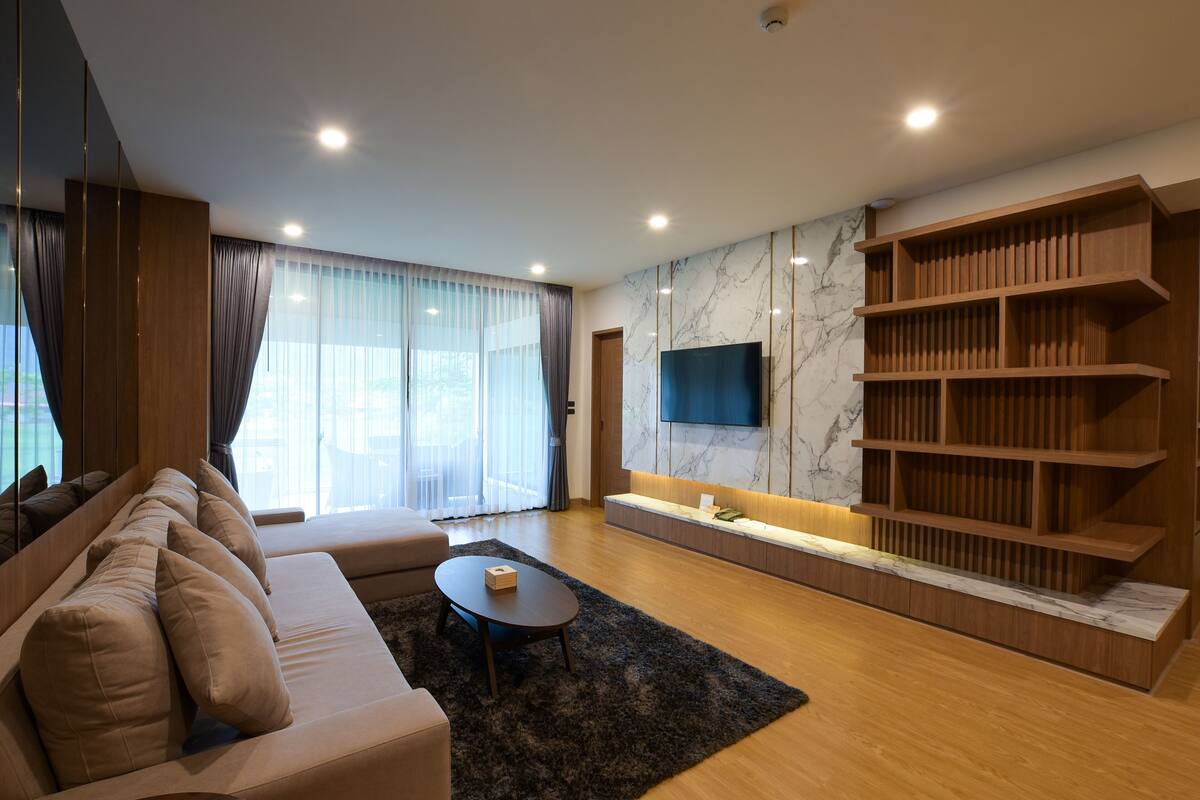 A modern living room with a sofa, a coffee table, a TV, and a wooden bookshelf.
