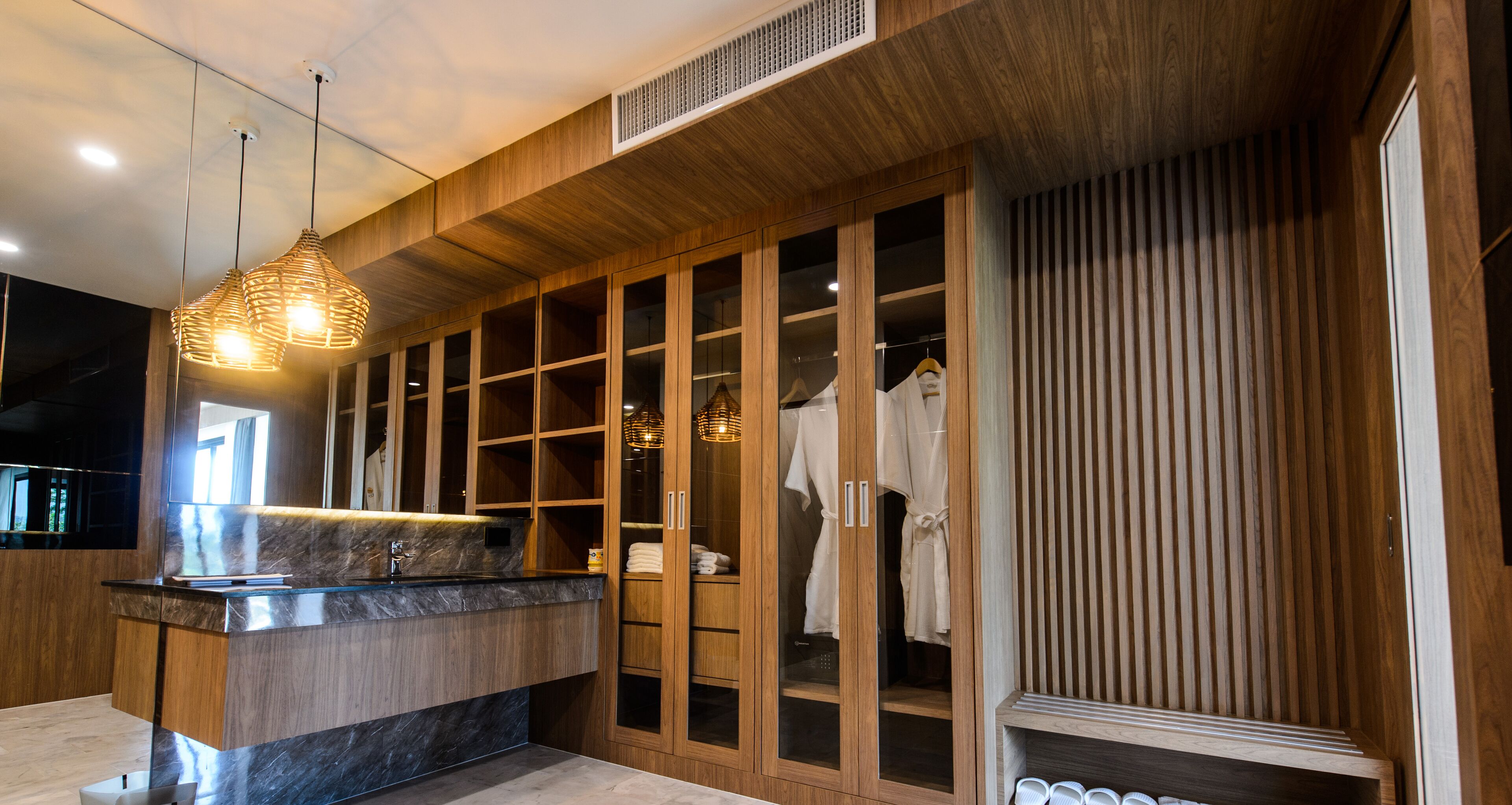 A modern bathroom with a wooden vanity, a glass shower enclosure, and a hanging light fixture.