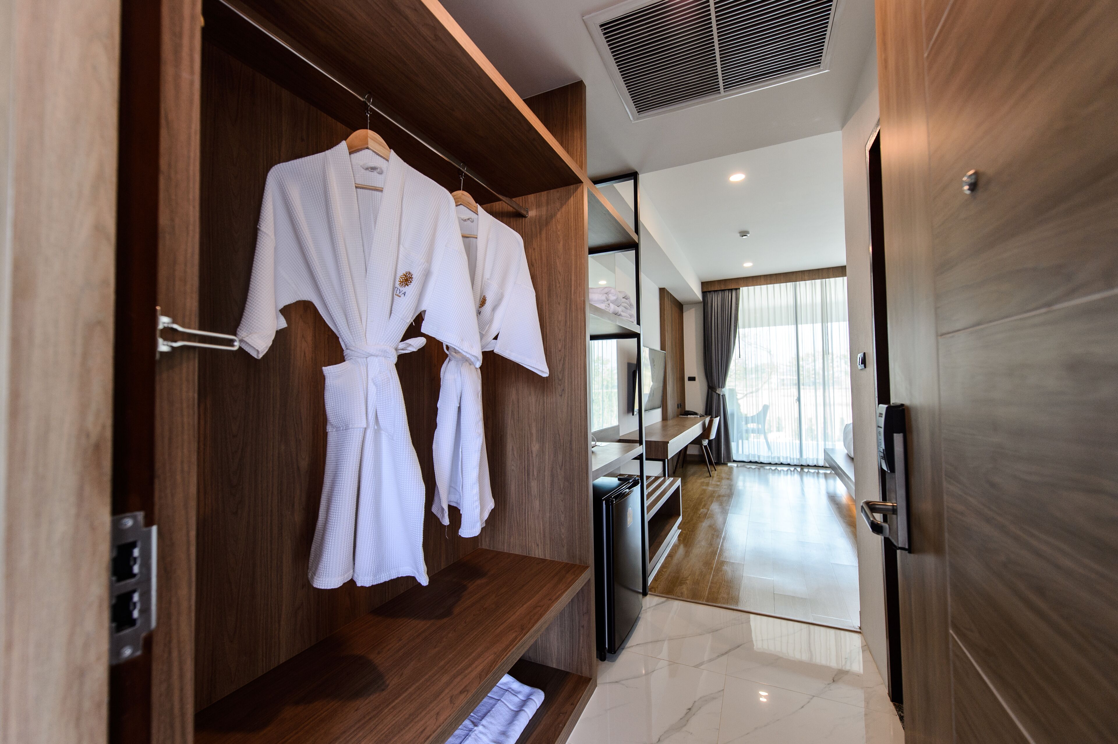 Ein Hotelzimmer mit Holzwandverkleidung, einem eingebauten Wandschrank mit Roben und einem Schreibtisch sowie einem großen Spiegel.