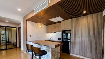 Cocina moderna con isla de madera, electrodomésticos negros y una lámpara colgante original.