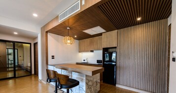 Cocina moderna con isla de madera, electrodomésticos negros y una lámpara colgante original.