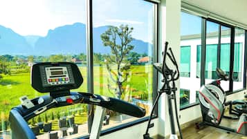 A home gym with a treadmill, stationary bike, and exercise equipment, overlooking a scenic view of mountains and greenery.