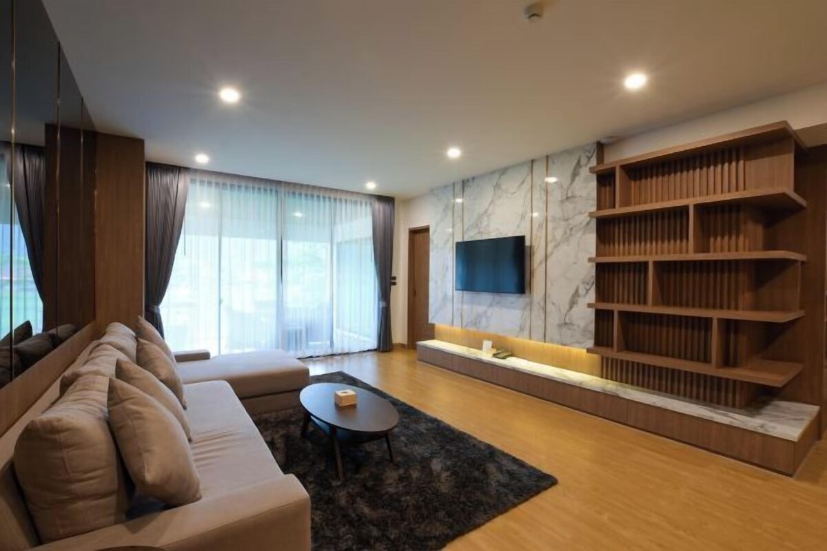 A modern living room with a sofa, a coffee table, a TV, and a wooden bookshelf.