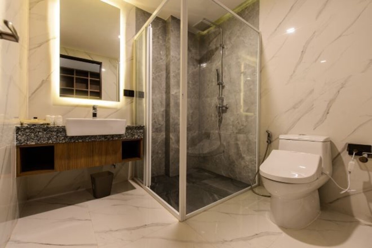 A modern bathroom with a glass-enclosed shower, a marble sink, and a toilet.