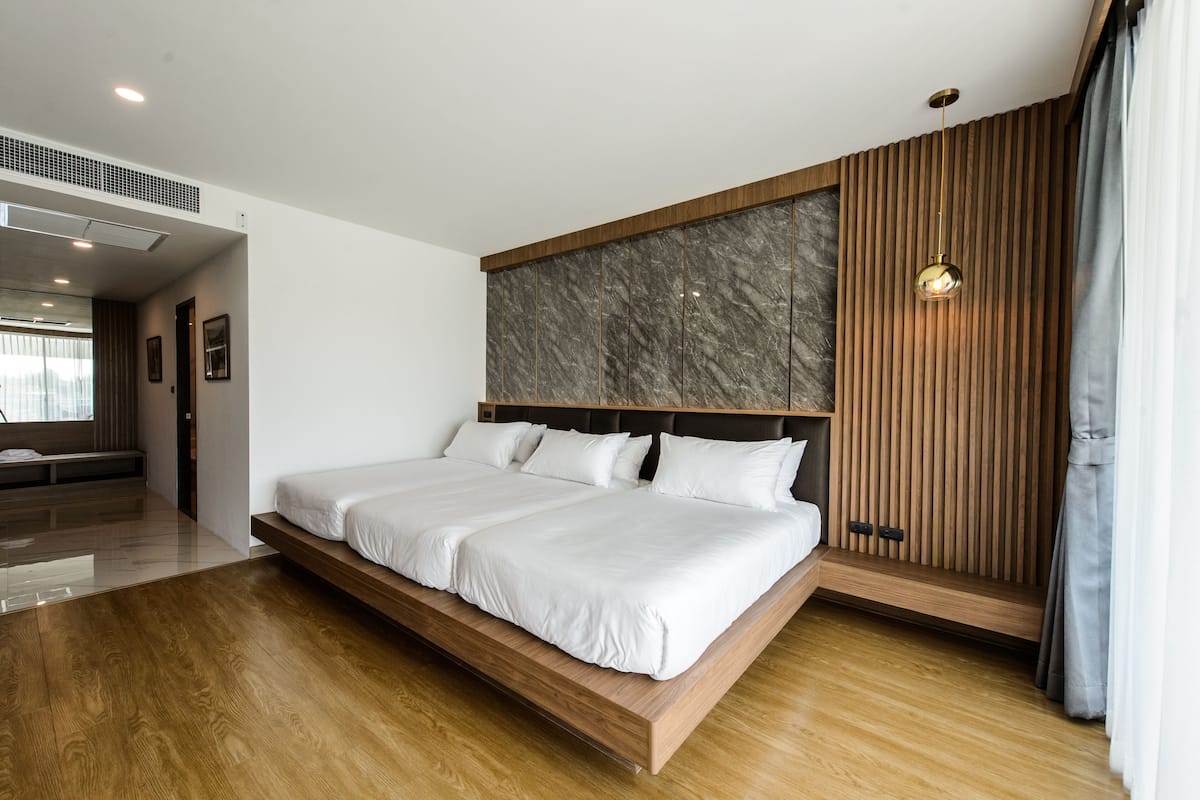 A modern bedroom with a large bed, wooden paneling, and a marble accent wall.