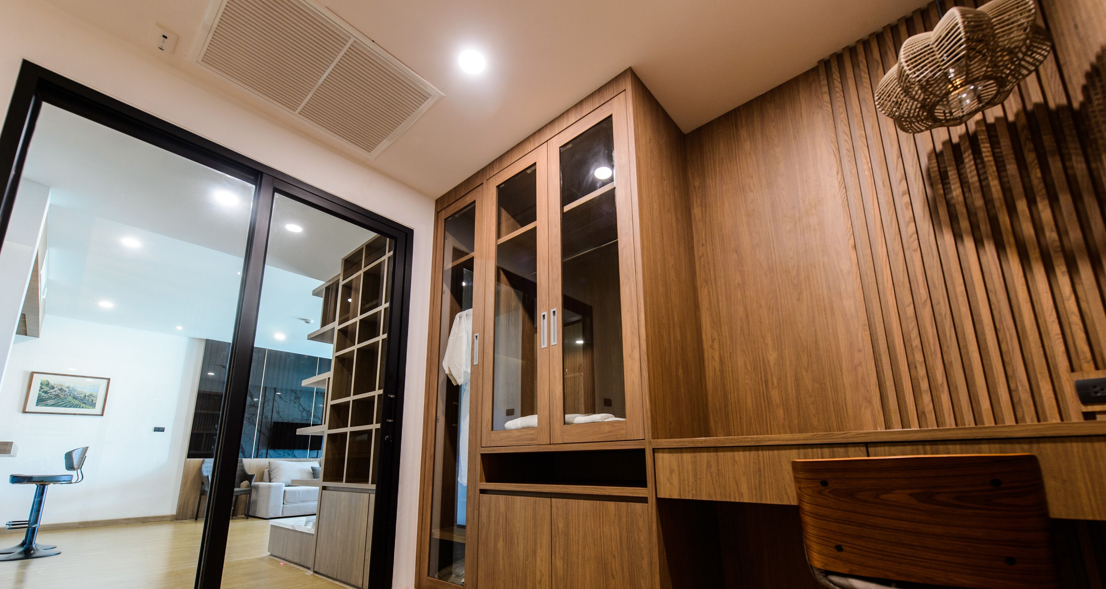 A modern interior with a wooden cabinet, a glass door, and a seating area with a chair and a table.