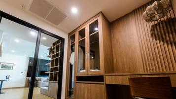 A modern interior with a wooden cabinet, a glass door, and a seating area with a chair and a table.