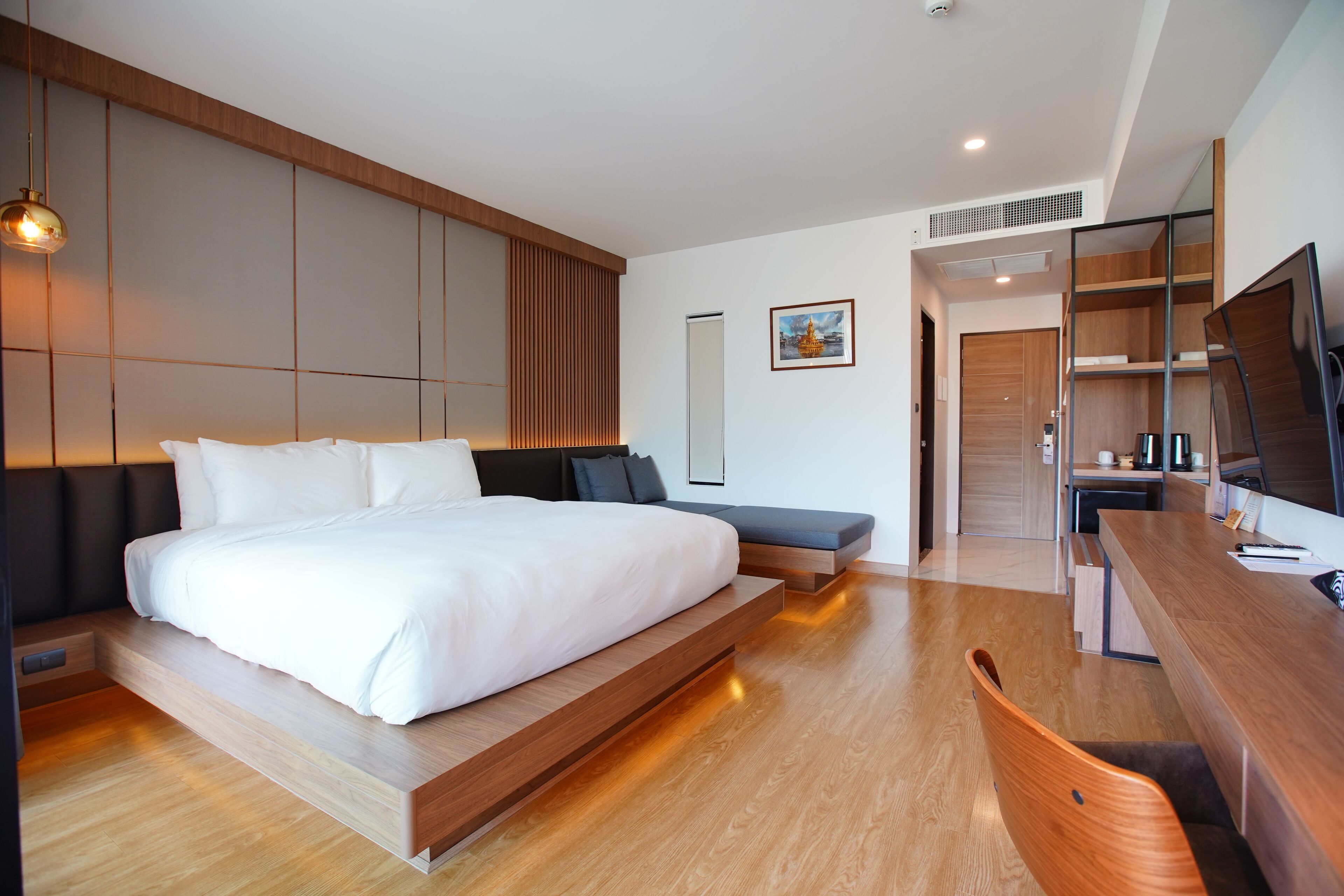 A modern hotel room with a large bed, a desk, and a seating area.