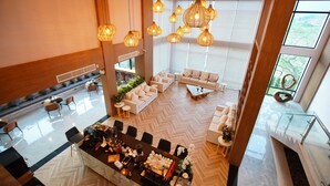 A spacious hotel lobby with a central bar, seating areas, and large windows offering views of the outdoors. - TEVA Valley Resort (Mae Sai)