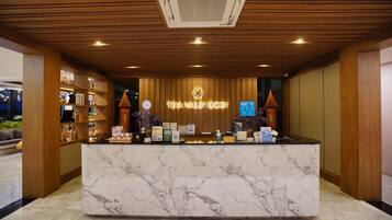 Un comptoir d’accueil au Teva Valley Resort, doté d’un comptoir en marbre, de panneaux en bois et d’une enseigne au-dessus.