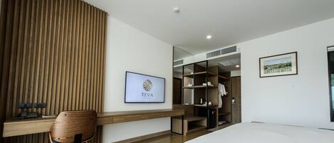 A modern hotel room with a wooden desk, a chair, a wardrobe, and a bed.