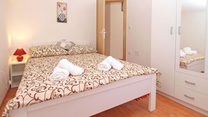 Una cama bien hecha con ropa de cama estampada, una lámpara de noche y un armario con espejo.