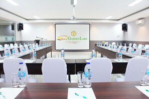 Ein Konferenzraum im Suni Garden Lake Hotel & Resort mit einem langen Tisch, Stühlen, Wasserflaschen und einer Präsentationsleinwand.
