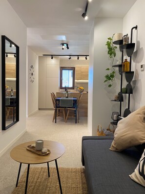 A modern living room with a sofa, a coffee table, and a dining area with a table and chairs.