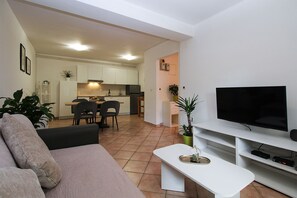 A living room with a sofa, a coffee table, a TV, and a kitchen in the background. - Apartment 1346/12667 (Istria - Pula), 1000m from the beach (Pula)