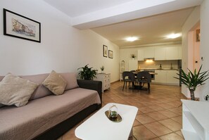 A living room with a sofa, a coffee table, and a dining area with chairs and a table. - Apartment 1346/12667 (Istria - Pula), 1000m from the beach (Pula)