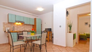 A compact kitchen with a dining table and chairs, a built-in oven, and a small dining area with a chair and a table. - Apartment 1346/12667 (Istria - Pula), 1000m from the beach (Pula)