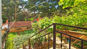 A staircase leading to a garden area with a view of a house with a red-tiled roof. - Apartment 1348/12670 (Istria - Pula), 100m from the beach (Pula)
