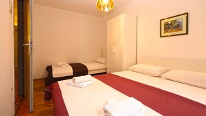 A hotel room with two beds, a wardrobe, a painting on the wall, and a door leading to another room. - Apartment 1348/12670 (Istria - Pula), 100m from the beach (Pula)