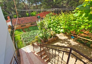 Staircase leads to an upper level amidst lush greenery and a brick pathway.