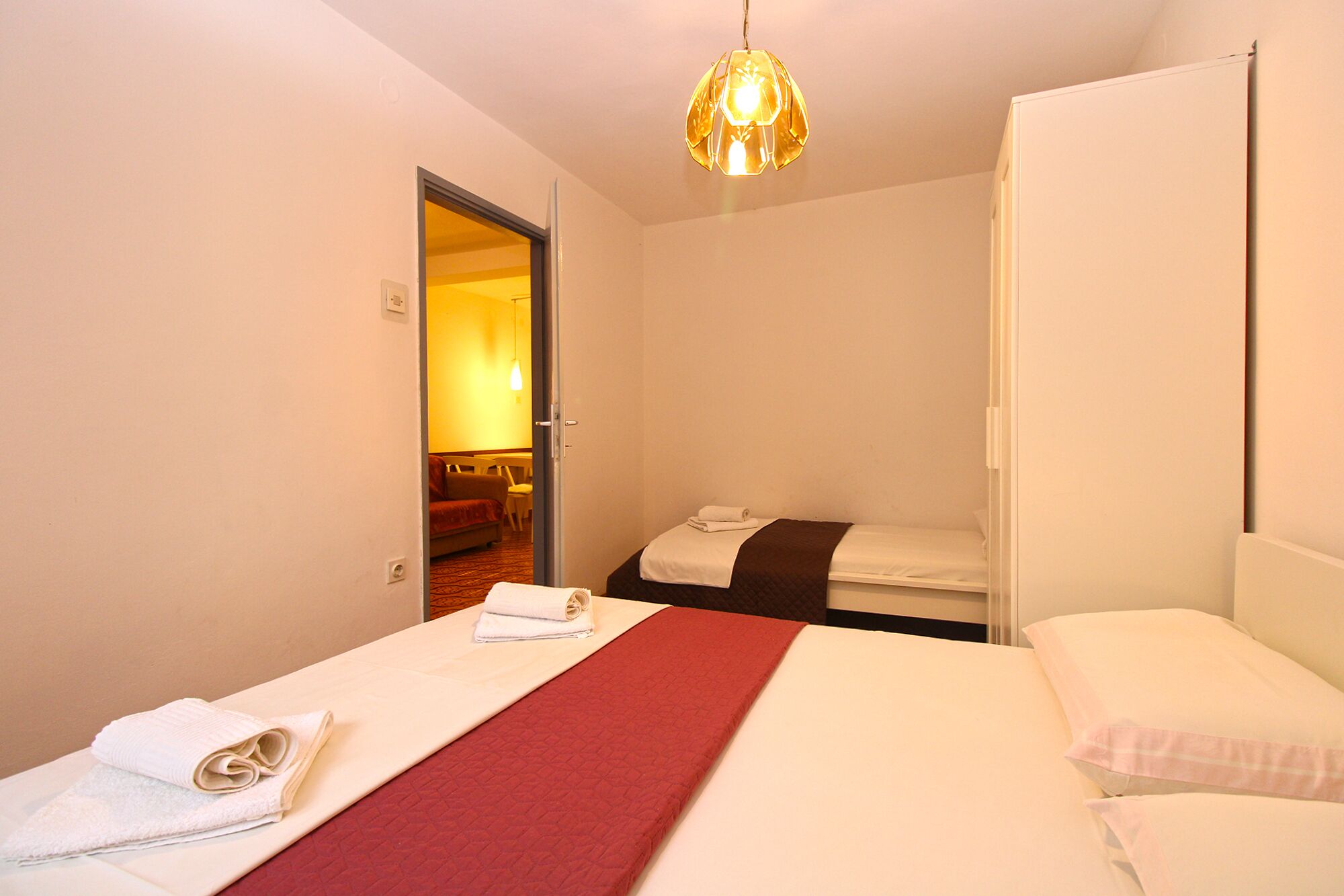 Une chambre d’hôtel avec un lit, une couverture rouge et un luminaire suspendu.