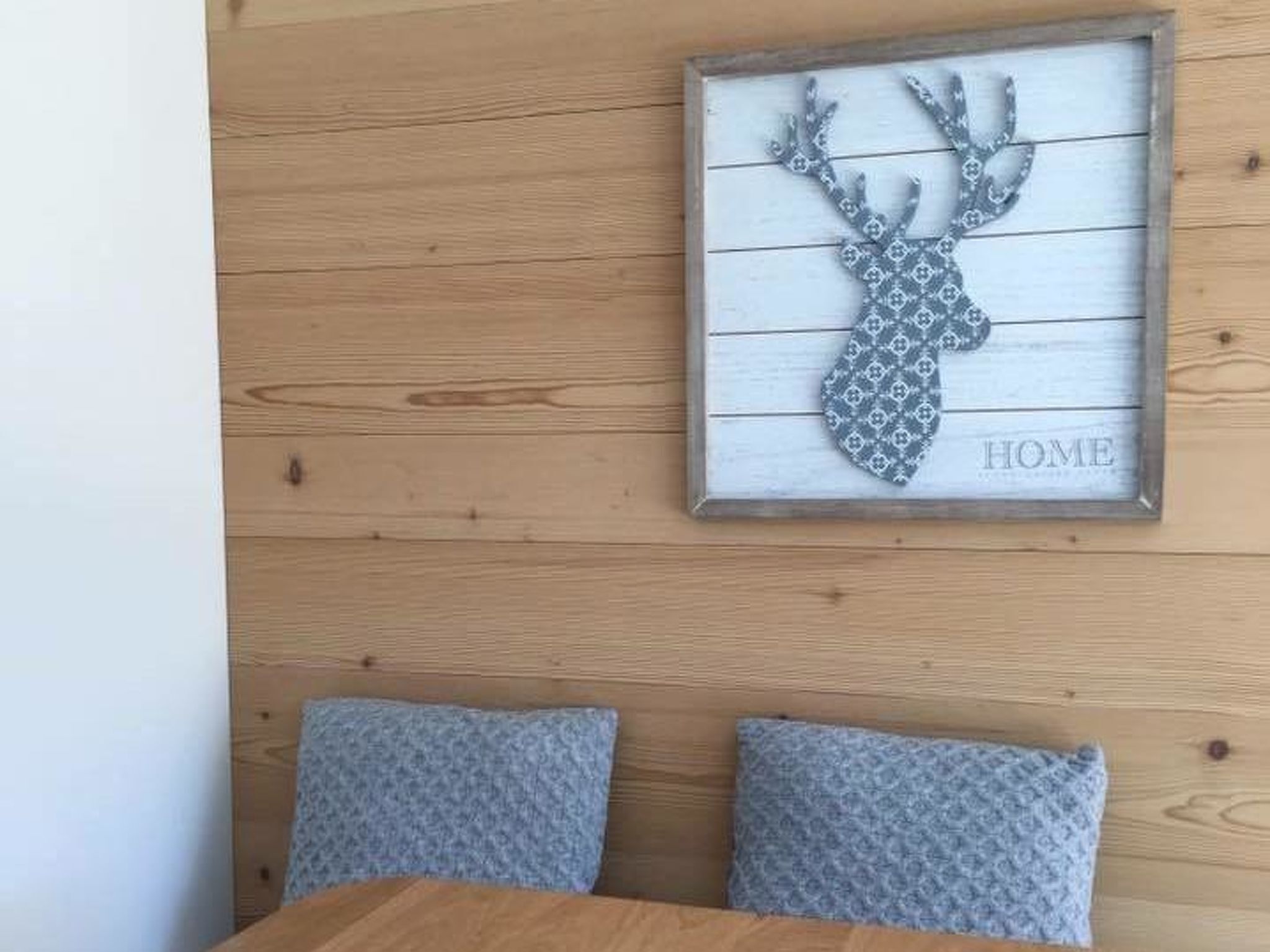 Ein gerahmtes Bild eines Rehgeweihs an einer Holzwand, mit dem Wort "HOME".