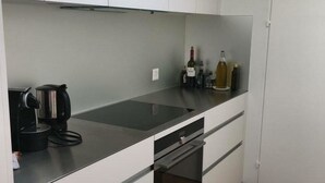 A modern kitchen with a black countertop, white cabinets, and a built-in oven. - Turmalin 2. Stock by Interhome (Lenk)