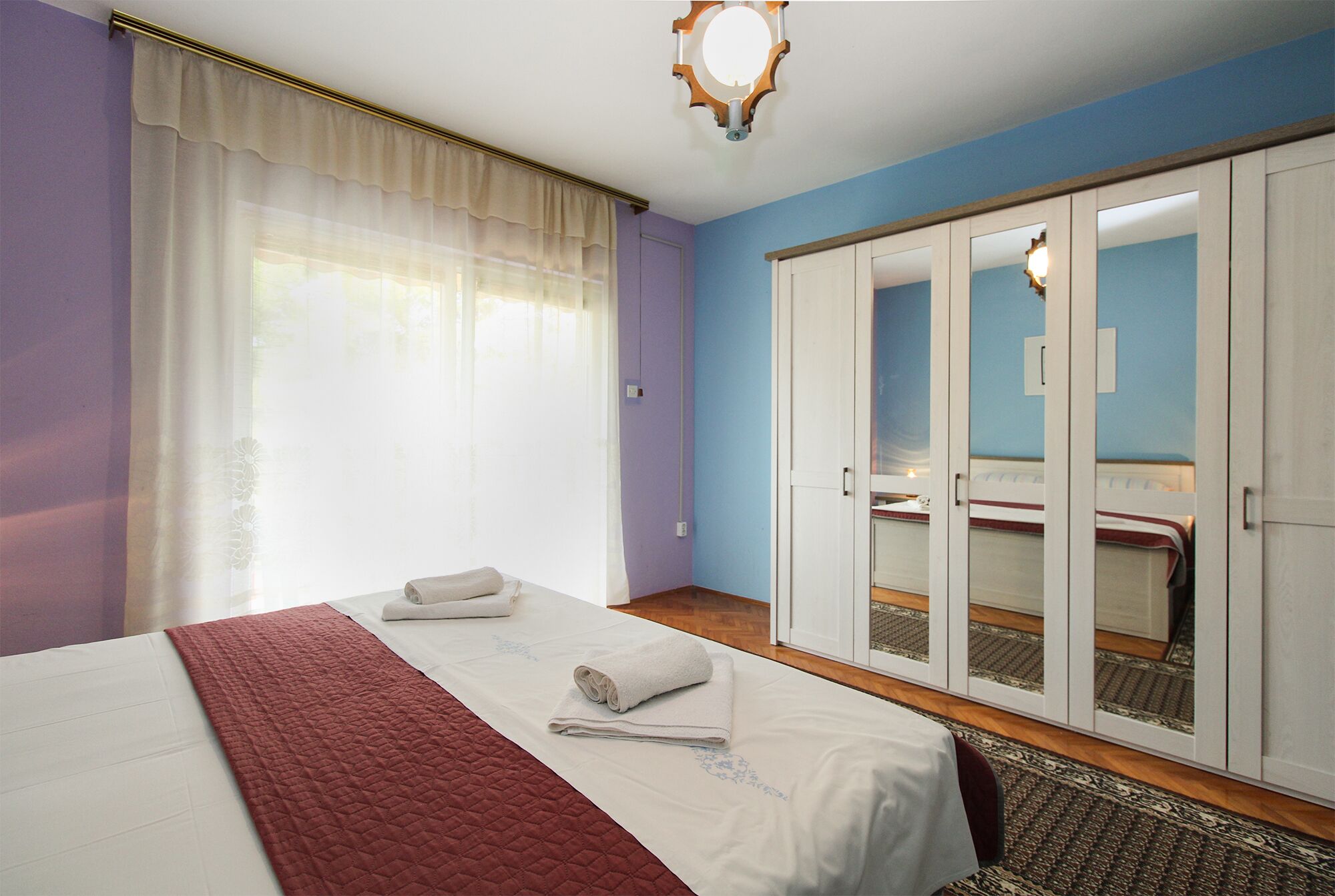 Een hotelkamer met een bed, een kledingkast en een groot raam met gordijnen.