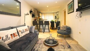 A living room with a sofa, a coffee table, a TV, and a kitchen in the background. - Apartment 1352/12718 (Istria - Pula), 750m from the beach (Pula)