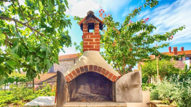 A brick-built outdoor oven with a chimney, surrounded by greenery and a stone wall. - Apartment 1352/12718 (Istria - Pula), 750m from the beach (Pula)