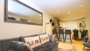 A living room with a grey sofa, a coffee table with drinks, a kitchen in the background, and a large mirror on the wall. - Apartment 1352/12718 (Istria - Pula), 750m from the beach (Pula)