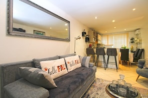 A living room with a grey sofa, a coffee table with drinks, a kitchen in the background, and a large mirror on the wall. - Apartment 1352/12718 (Istria - Pula), 750m from the beach (Pula)
