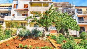 A multi-story residential building with balconies, satellite dishes, and a garden area with various plants. - Apartment 1352/12718 (Istria - Pula), 750m from the beach (Pula)
