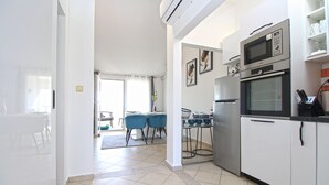A modern kitchen with stainless steel appliances, a dining area with blue chairs, and a view to the outside. - Apartment 1352/12722 (Istria - Pula), 750m from the beach (Pula)